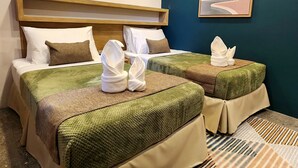 Une chambre d’hôtel avec deux lits, une tête de lit en bois, un climatiseur fixé au mur et un tableau encadré.