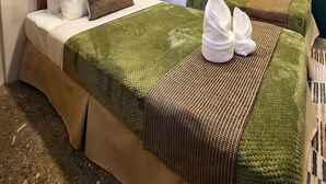 A hotel room with two beds, a wooden headboard, a wall-mounted air conditioner, and a framed picture.