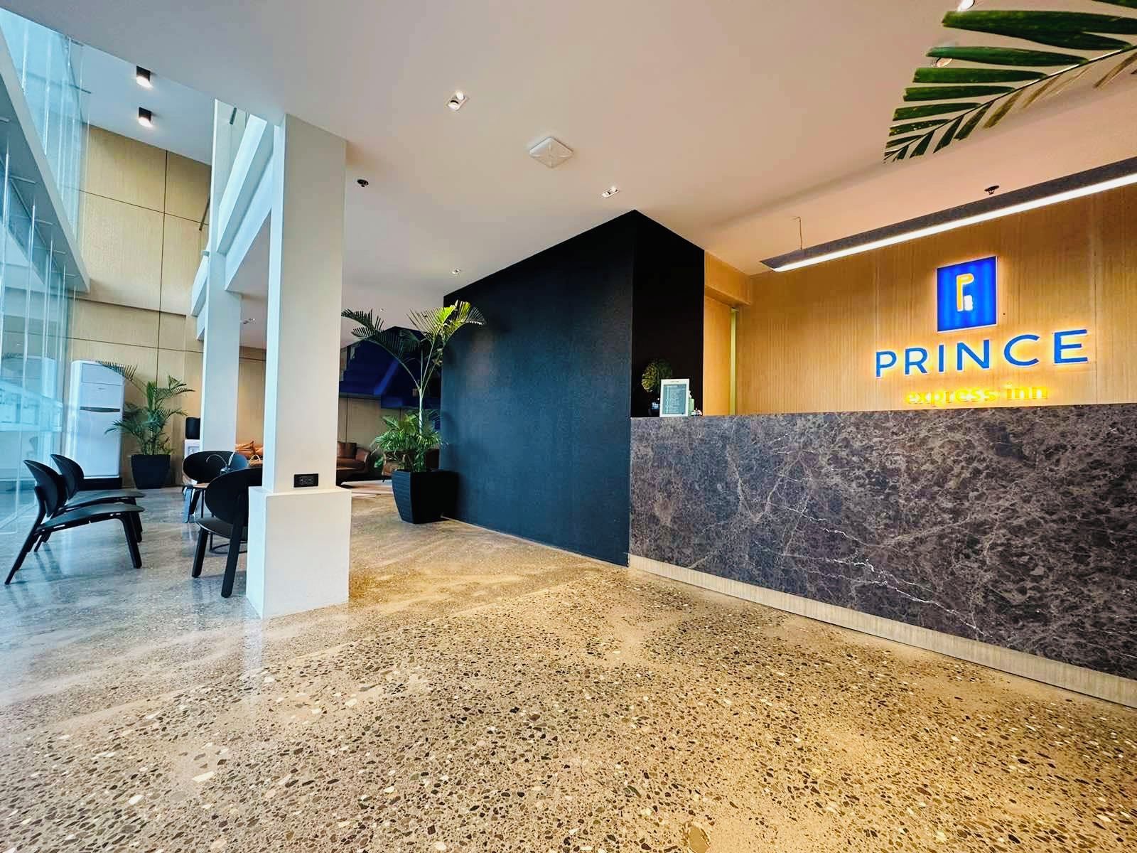 Ein Hotel-Rezeptionsbereich mit einer Marmor-Theke, einem Schild mit der Aufschrift 'PRINCE ACCESS' und einem modernen Interieur.