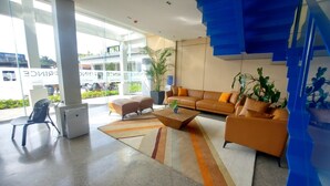 Un hall d’entrée moderne avec un canapé, des fauteuils, une table basse et une grande fenêtre.