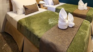 A hotel room with two beds, a wooden headboard, a wall-mounted air conditioner, and a framed picture.