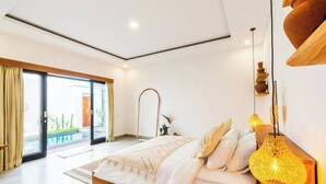 Une chambre moderne dotée d’un grand lit, d’une porte vitrée donnant sur un balcon et d’un luminaire suspendu original.