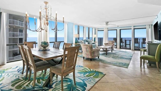 A spacious living room with a large dining table, comfortable seating, and a view of the ocean.
