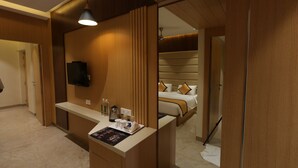 Een hotelkamer met houten details, een bed met hoofdeinde, een nachtkastje met een flatscreen televisie, en een spiegel die de kamer weerspiegelt.