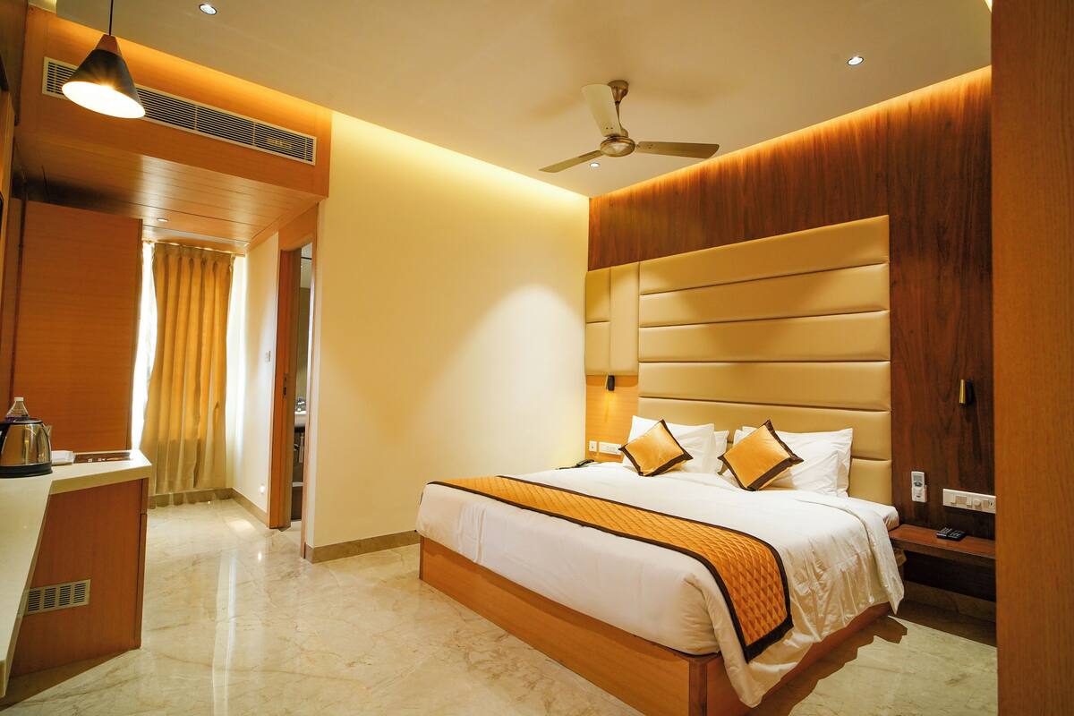 A hotel room with a large bed, a desk, a ceiling fan, and a wooden headboard.