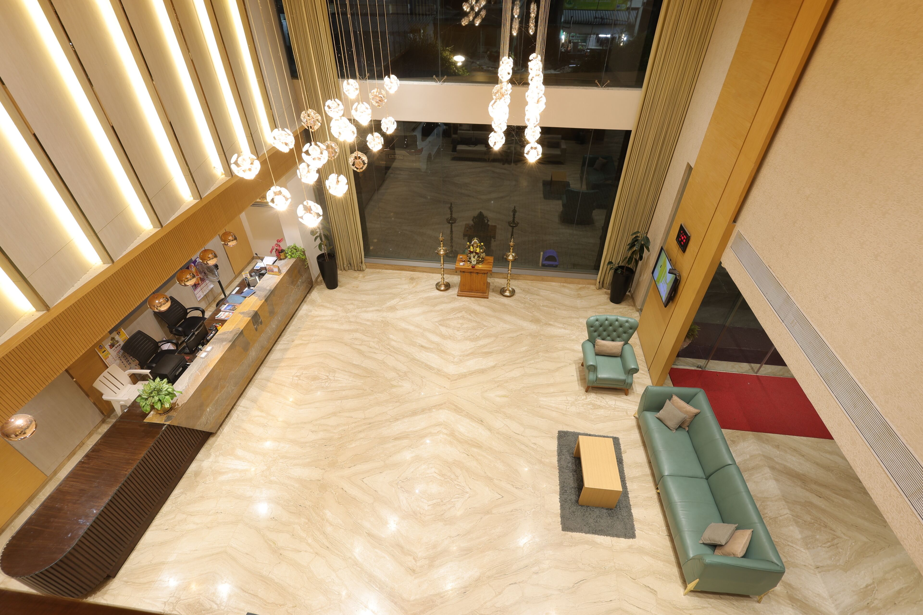 Un hall de hotel con mostrador de recepción, zona de estar y un ventanal grande.