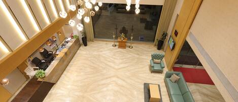 Un hall de hotel con mostrador de recepción, zona de estar y un ventanal grande.