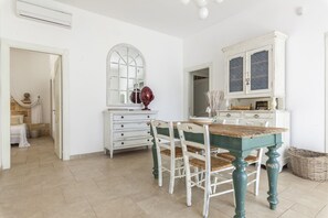 A room with a dining table, chairs, a white dresser, a mirror, and a window.