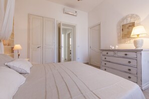 A bedroom with a bed, a dresser, a mirror, and a door leading to another room.