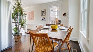 A dining area with a wooden table, chairs, a yellow bowl, and a potted plant.