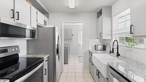 A modern kitchen with stainless steel appliances, white cabinetry, and a granite countertop.