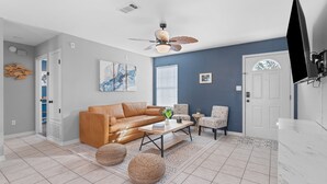 A living room with a leather sofa, a coffee table, and a ceiling fan.