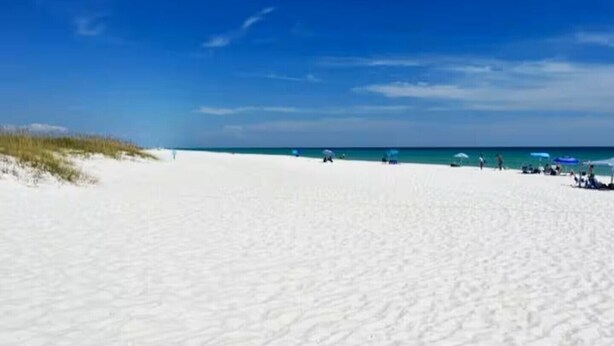 A beach with white sand and a clear blue sky.