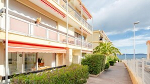 Un hotel de varios pisos con balcones, una zona de estar al aire libre cubierta y vistas al mar.