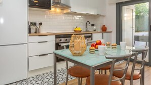A modern kitchen with white cabinets, a black microwave, and a glass table with chairs.