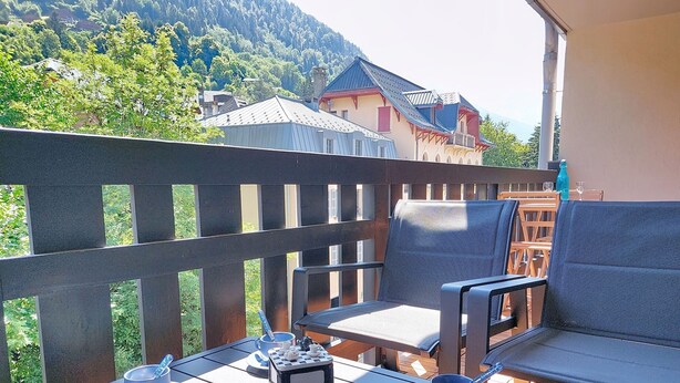 Un balcon avec une table préparée pour le thé, deux chaises et une vue imprenable sur les montagnes.