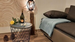 Ein gemütlicher Wohnbereich mit einem runden Beistelltisch, einer dekorativen Lampe, einem Sofa mit blauer Decke und Holzboden.