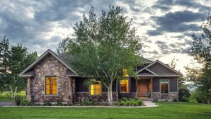 A two-story house with a stone facade, large windows, and a well-maintained lawn. - Month long Rental- Teton Springs Home 4 Bedroom (Victor)