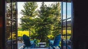 A room with a large glass door leading to an outdoor deck with blue Adirondack chairs and a small table. - Month long Rental- Teton Springs Home 4 Bedroom (Victor)