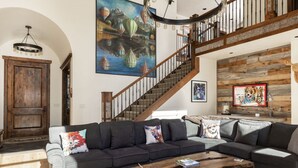 A spacious living room with a large sectional sofa, a wooden coffee table, and a staircase leading to an upper level. - Month long Rental- Teton Springs Home 4 Bedroom (Victor)