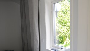A bedroom with a bed, a window, and a glass jar on the windowsill.