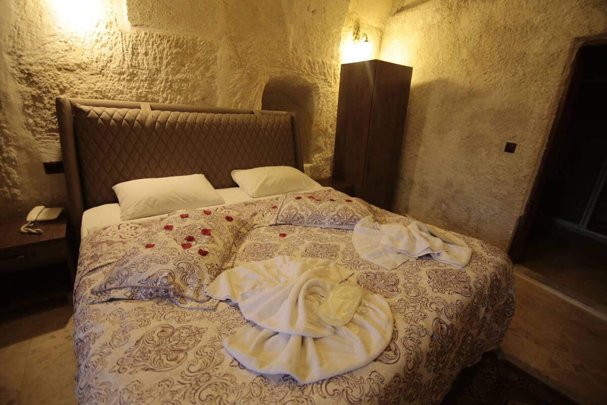 Una cama con una colcha estampada, almohadas y una toalla.