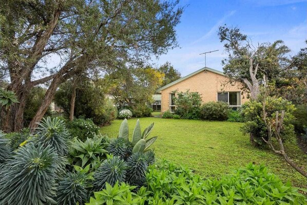 Enjoy a serene garden with lush greenery and a single-story home with a pitched roof.