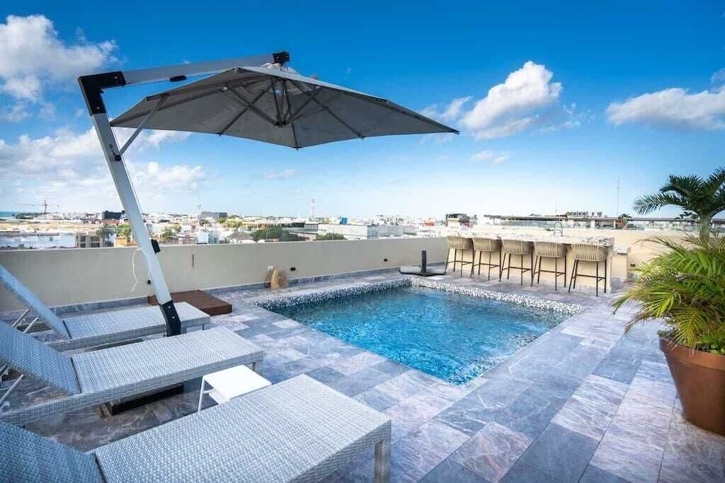 Shared rooftop jacuzzi with shaded loungers