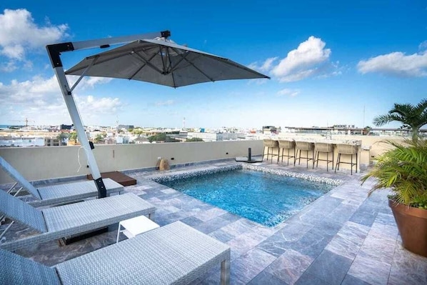 Shared rooftop jacuzzi with shaded loungers