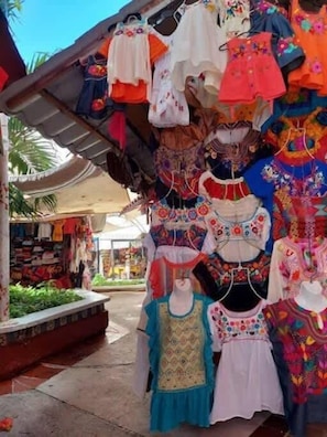 A variety of colorful children's clothing displayed in a market setting.