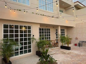 A building with large windows, outdoor seating, and string lights.
