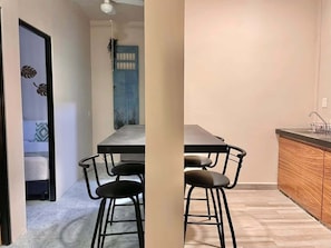 A compact living space with a dining area, kitchenette, and a door leading to a bedroom.