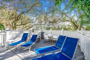 Eine Terrasse mit blauen Liegestühlen und einem Tisch, umgeben von einem weißen Zaun.