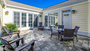 Eine Terrasse mit Gartenmöbeln und einem überdachten Bereich mit Schiebeglastüren.