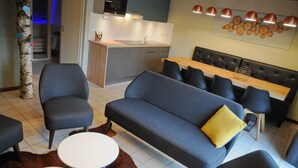 Een moderne woonkamer met een bank, stoelen en een eettafel.