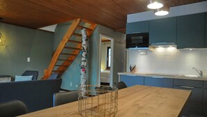 Een moderne keuken met houten kasten, een houten eettafel en een trap naar een andere kamer.