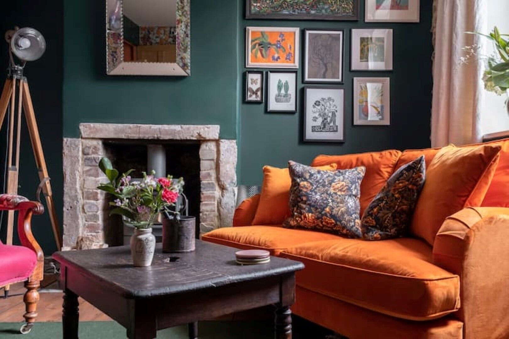 A cozy living room with a fireplace, a sofa, and a table with a vase of flowers.