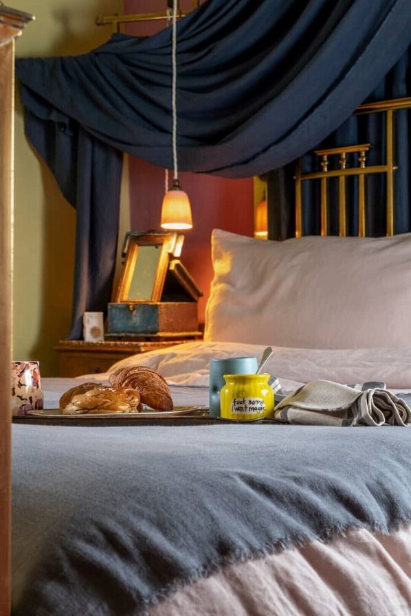 A neatly made bed with a blanket, a bedside lamp, a small table with a cup and a jar, and a window with curtains. - Conde Nast voted top Cotswold holiday let (Wingfield)