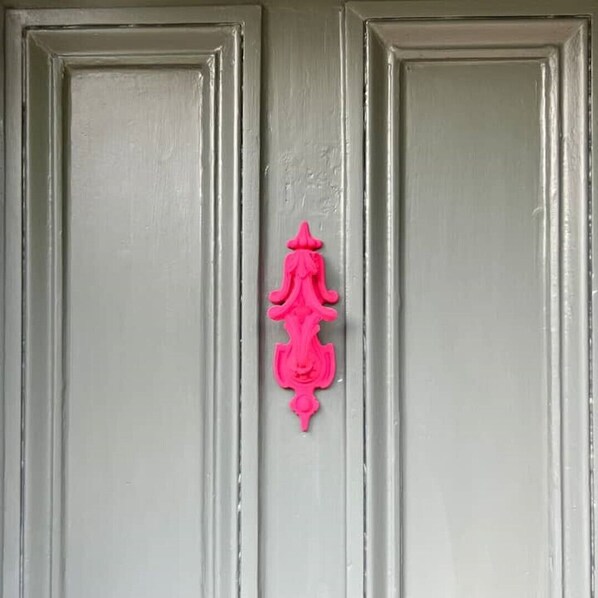 Una puerta con un tirador rosa decorativo.