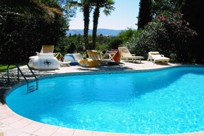 A clear blue swimming pool surrounded by lounge chairs and umbrellas, with a view of trees and mountains in the background. - Frejus Villa with Private Pool & Beach (Frejus)