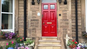 Una puerta roja con un cartel que dice "Welcome to Robertswood House" encima.