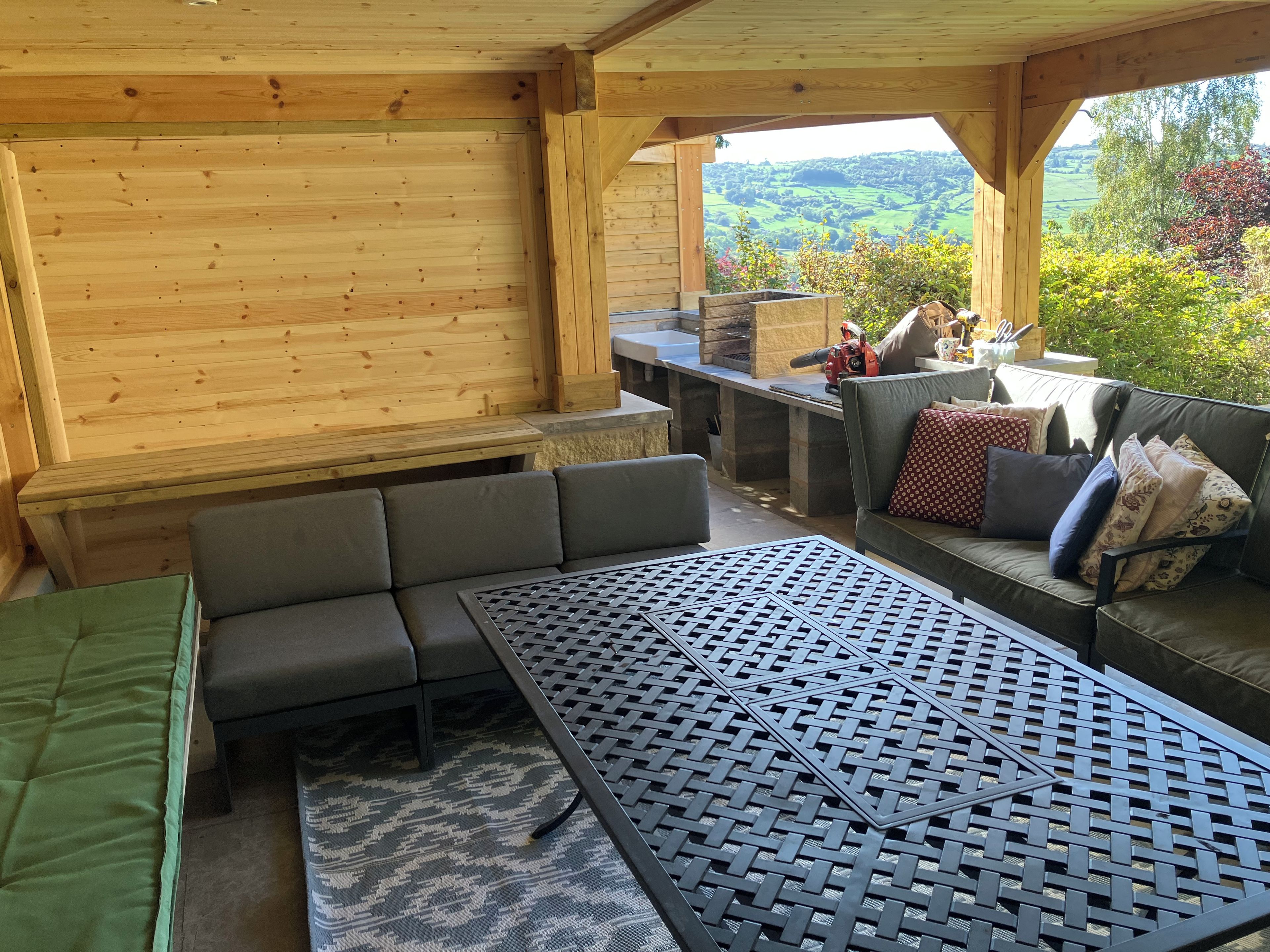 A wooden interior with a sofa, a table, and a view of the outdoors.