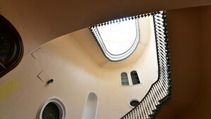 Un escalier en colimaçon orné d’une rampe décorative et doté d’une fenêtre circulaire en bas.
