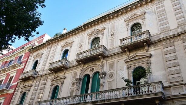 Un bâtiment historique doté d’éléments architecturaux raffinés, notamment des balcons décoratifs et des fenêtres en arc de cercle.
