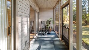 A covered porch with a rocking chair and a potted plant.