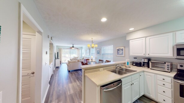 A modern kitchen with white cabinets, a built-in oven, a microwave, and a dishwasher. - Fairway Escape Modern 3BR with Scenic Views (Pawleys Island)