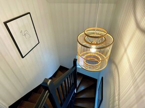 A staircase with a wooden railing and a hanging light fixture.