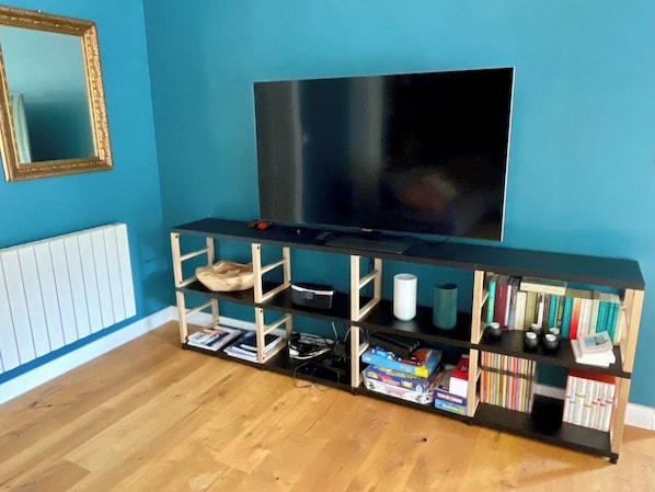 A room with a wooden entertainment unit, a television, and a radiator.