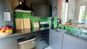 Eine moderne Küche mit grünen Fliesen, einem eingebauten Backofen und einer schwarzen Dunstabzugshaube.