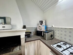 Een kleine keuken met een gasfornuis, een broodrooster en een waterkoker.